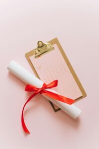 Elegant diploma with red ribbon, placed on a clipboard with a calendar, symbolizing achievement and planning.